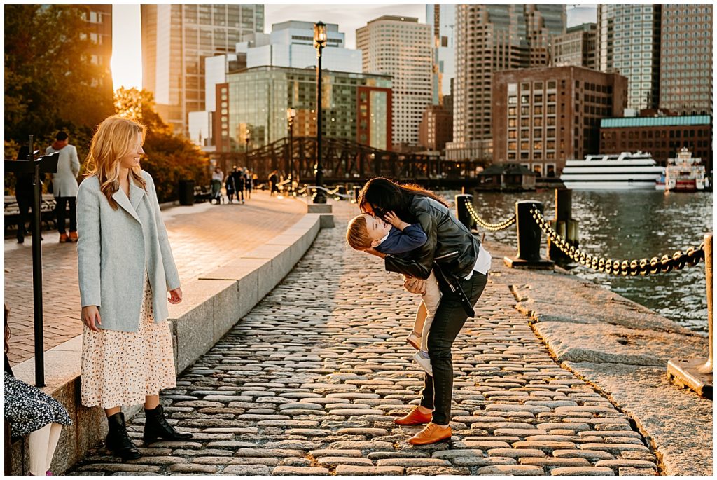Mother and son dancing on pavers in front of Boston Buildings.
