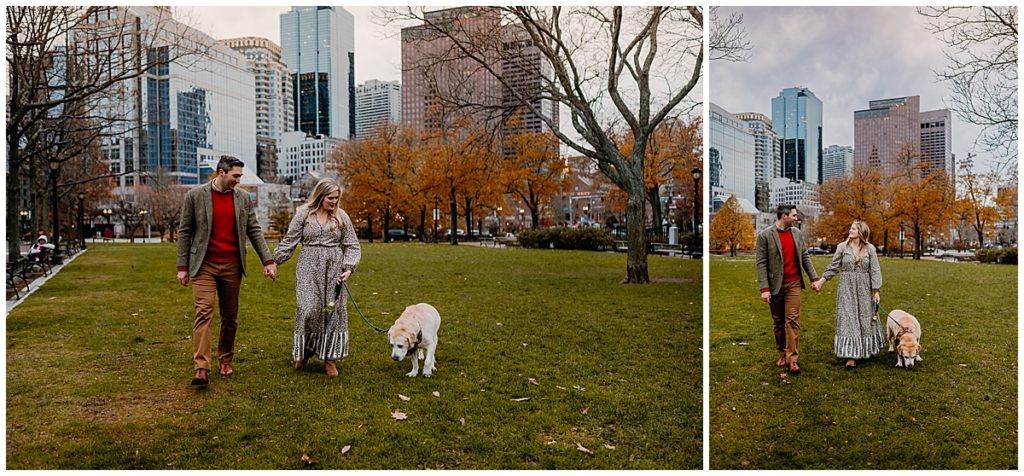 man, woman and dog walking in a park with Boston buildings in the background.
