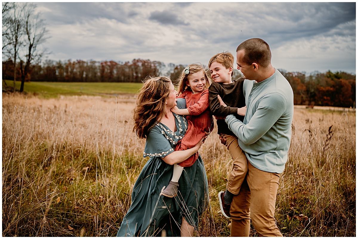 Family dancing in a field wearing a flowy dress and smiling.