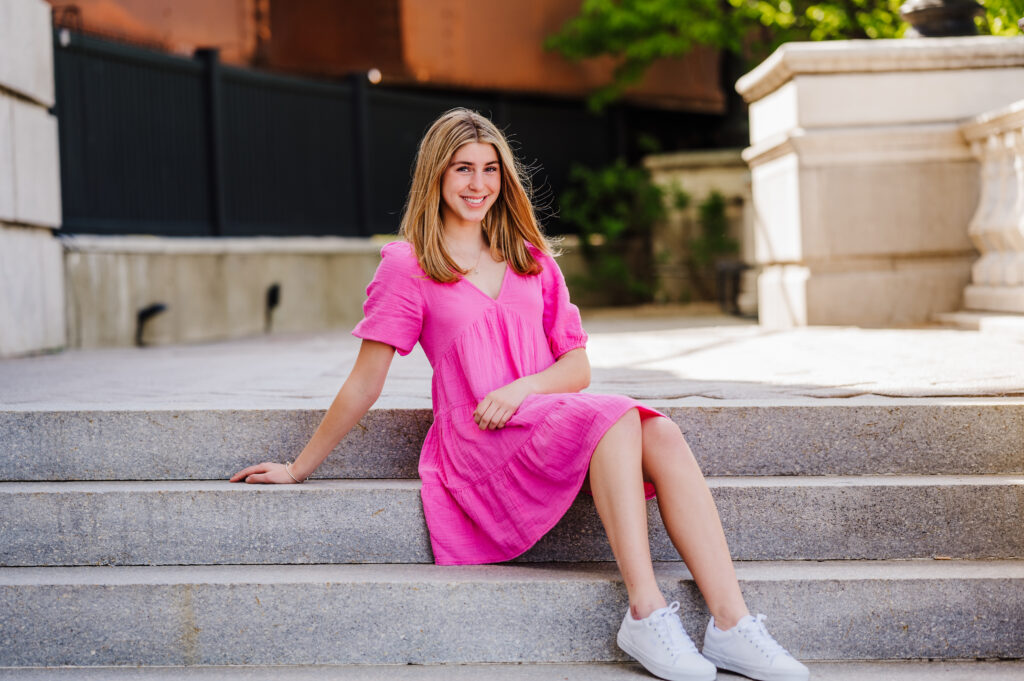 Girl sitting on stairs wearing a pink dress.