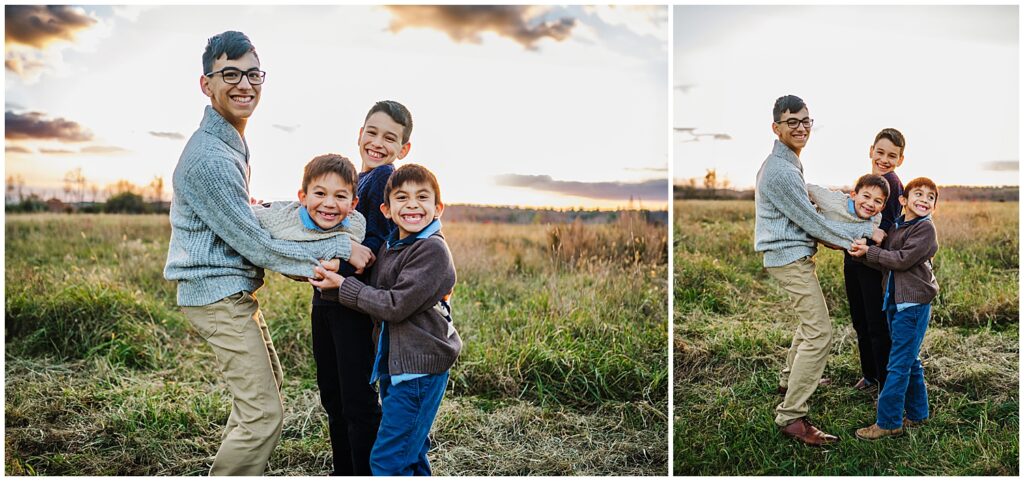 Boys in a Boston field holding their youngest brother and throwing him in the air.

