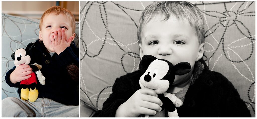 1 year old boy sitting in a chair sucking on the ear of Mickey Mouse