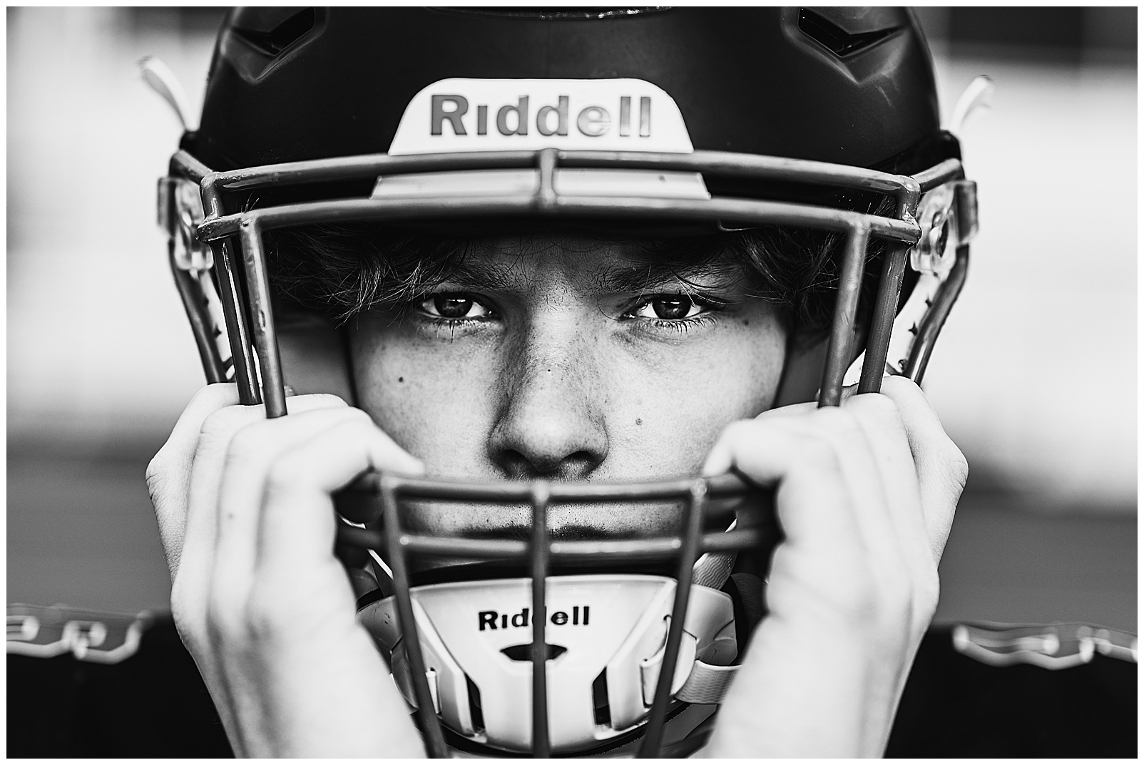 High school student wearing helmet and looking into camera during Boston Sports Photography capturing high school game action