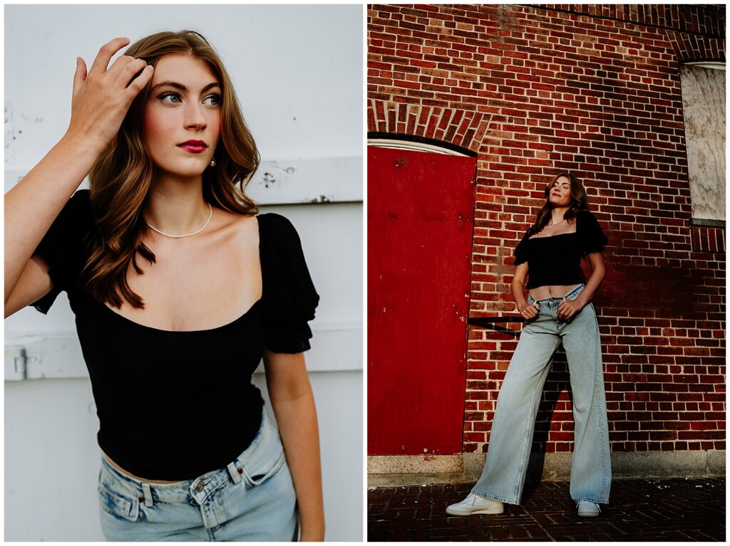 Senior girl in a black top and light jeans posing against a brick building and sitting on concrete steps for an urban-style senior portrait look.