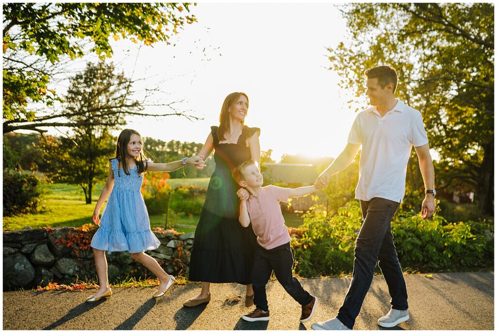 Family walking in a line holding hands and interacting and laughing together during a lifestyle family session in Hopkinton, MA