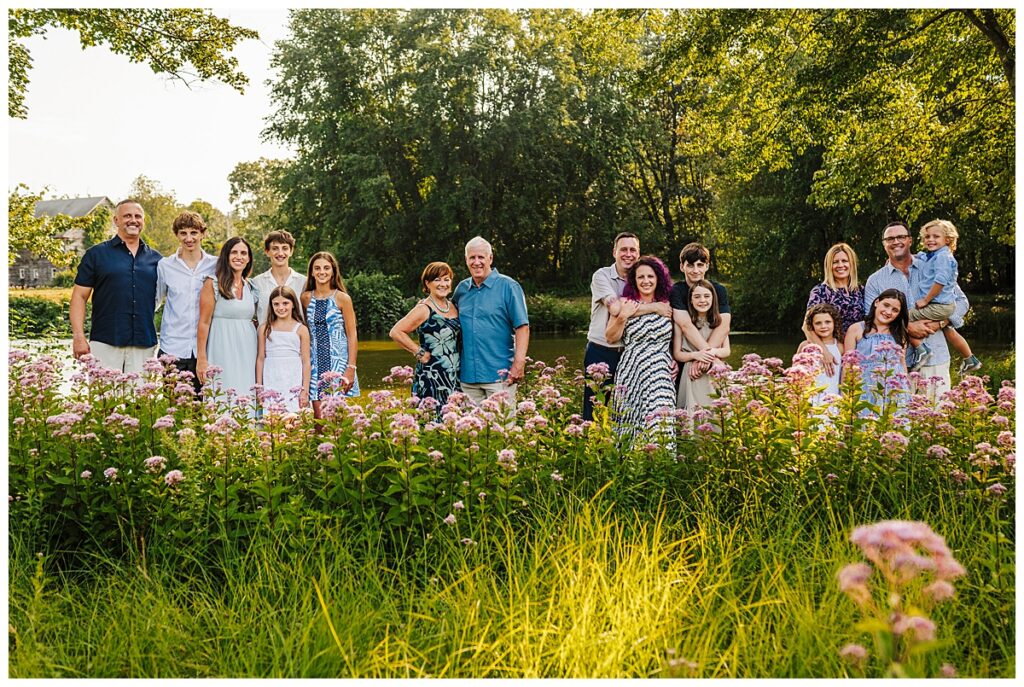 Large extended family portrait in pink wildflowers along the water